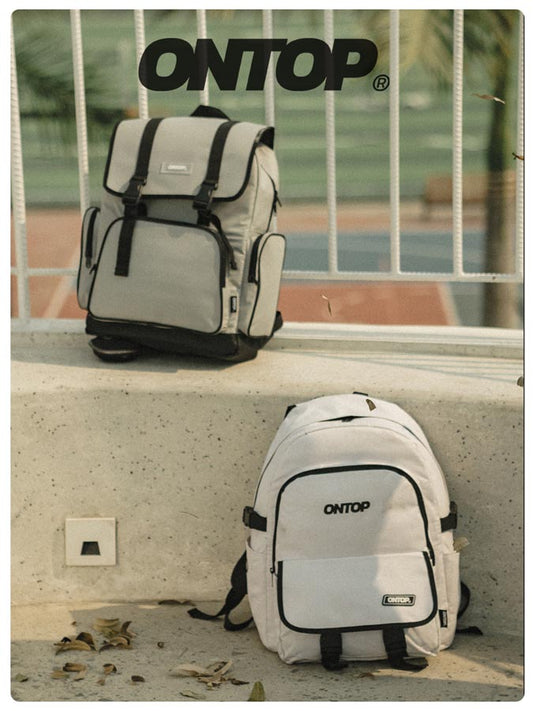 Two backpacks with 'ONTOP' branding on a concrete ledge.