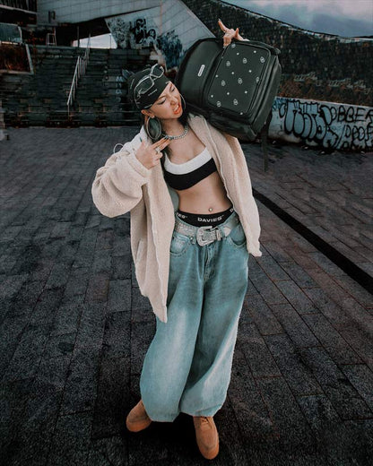 Person holding a suitcase on a rooftop with graffiti in the background