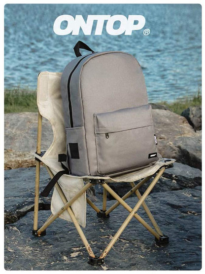 Gray backpack on a folding chair by a body of water with 'ONTOP' branding.