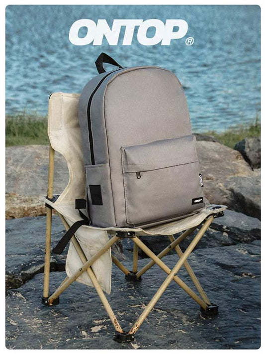 Gray backpack on a folding chair by a body of water with 'ONTOP' branding.