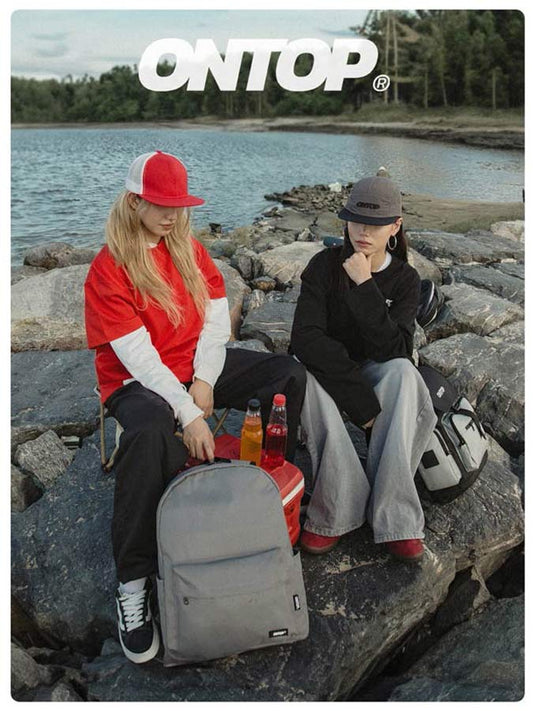 Two people sitting on rocks by a lake with 'ONTOP' branding.