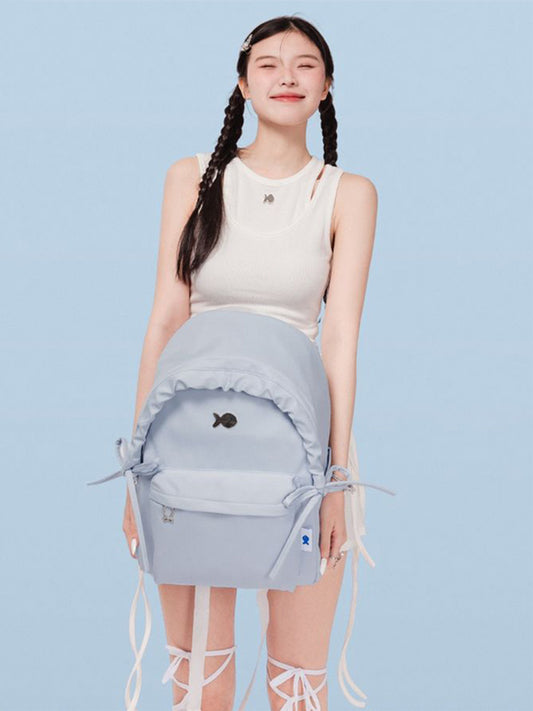 Person wearing a light blue backpack with a fish design on a light blue background