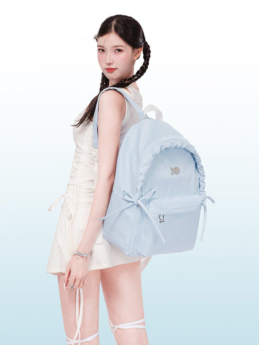 Woman holding a light blue backpack with a white background