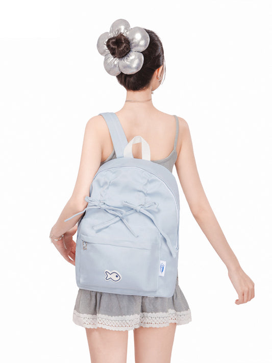 Person wearing a light blue backpack with a white logo on a white background
