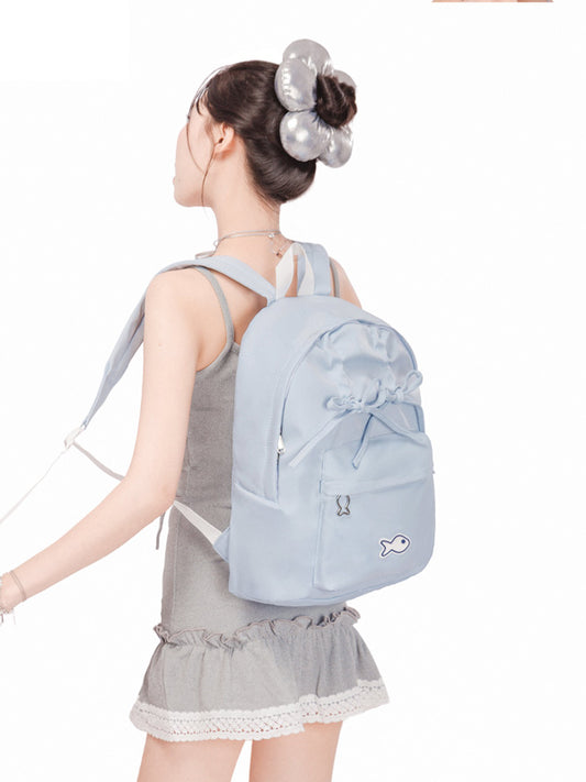 Woman wearing a light blue backpack with a white background
