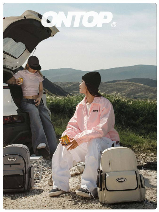 Two people sitting by a car with ONTOP branding in a scenic outdoor setting.