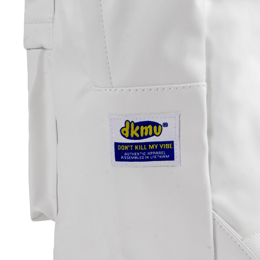 Close-up of a white garment with a 'dkmu' label on a white background