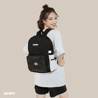 Person wearing a black backpack with 'DKMV' branding on a beige background