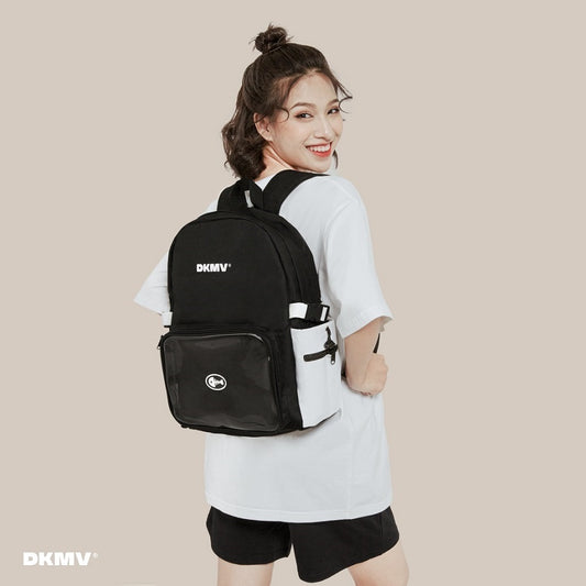Person wearing a black backpack with 'DKMV' branding on a beige background