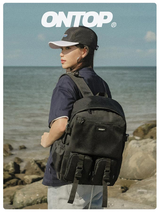 Person with a black backpack on a rocky beach with 'ONTOP' branding.