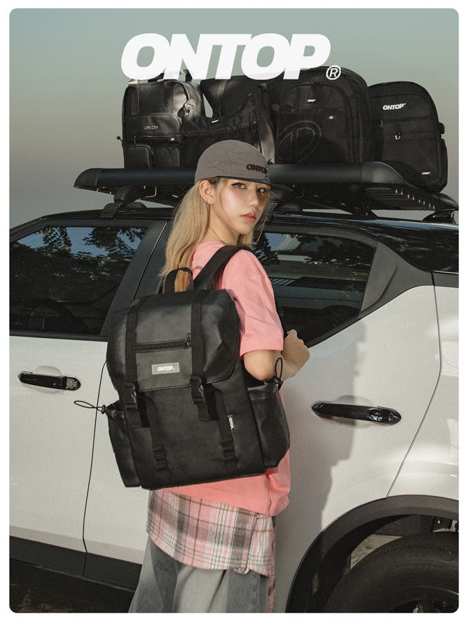 Person holding a black backpack with a car and roof racks in the background, featuring the 'ONTOP' brand.