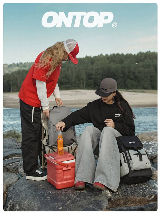 Two people by a lake with backpacks and coolers, featuring the 'ONTOP' brand.