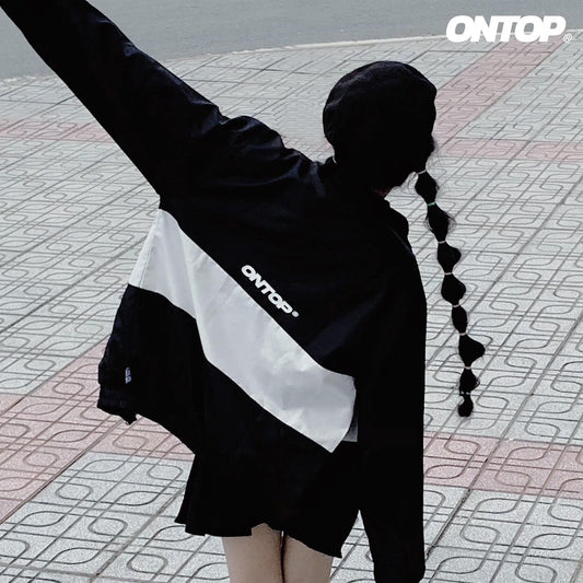 Person wearing a black and white jacket with 'ONTOP' branding on a patterned pavement.