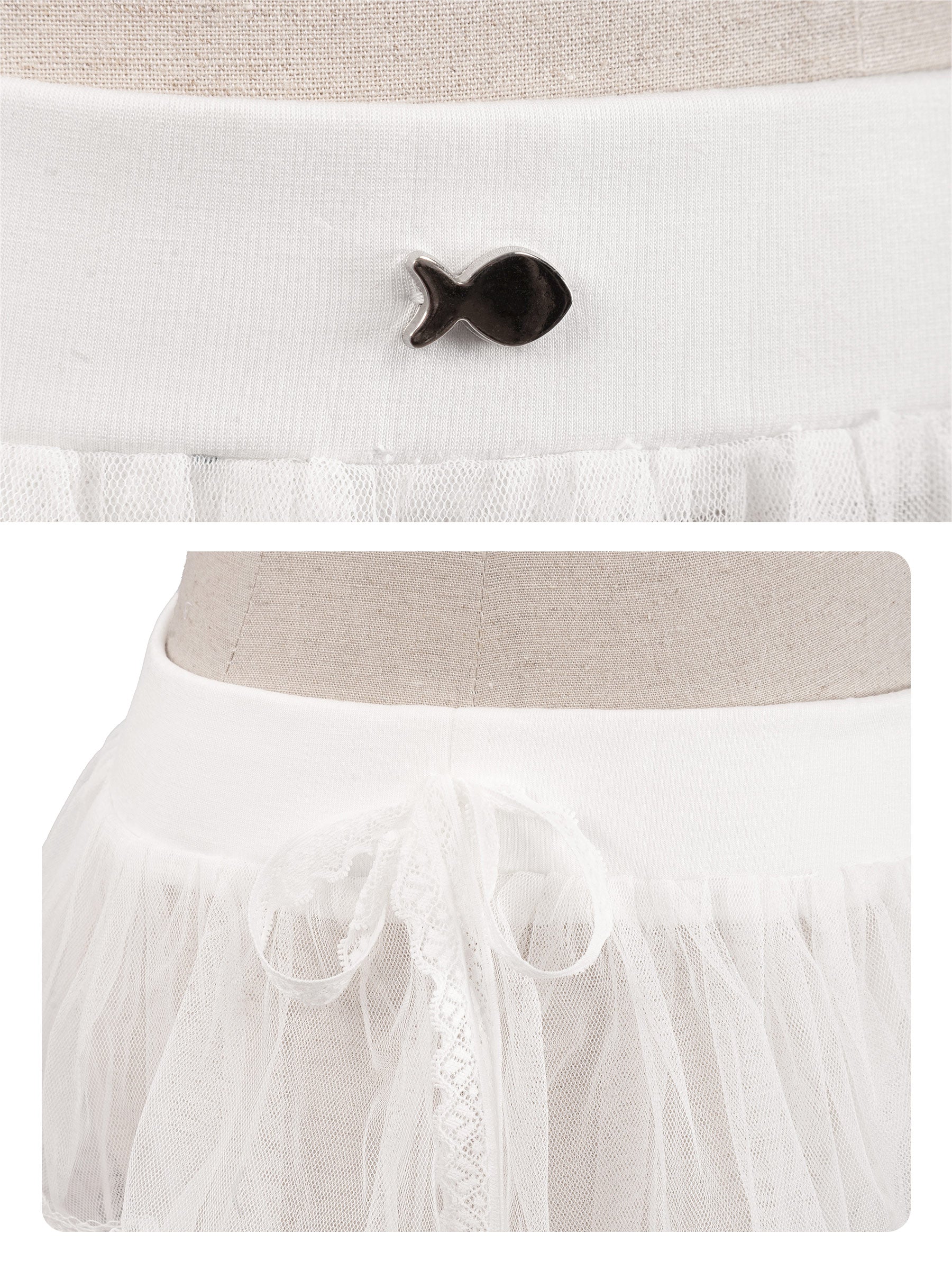 White dress with a black fish-shaped button on a neutral background