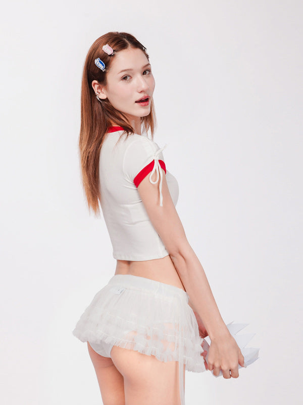 Woman wearing a white outfit with red accents on a plain background