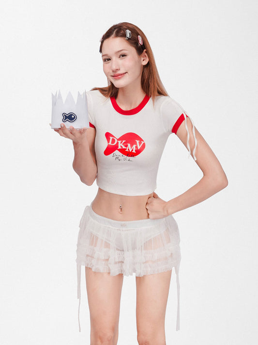 Woman wearing a white crop top with red accents and a skirt, holding a small white crown with blue details.