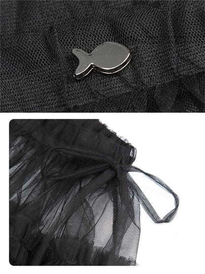 Black mesh bag with a fish-shaped metal clip on a textured black background.
