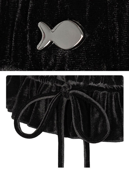Black velvet garment with silver fish-shaped brooch on a textured black background
