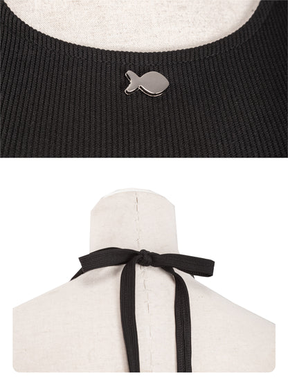 Black sweater with fish-shaped button and white garment with black ribbon on a mannequin.
