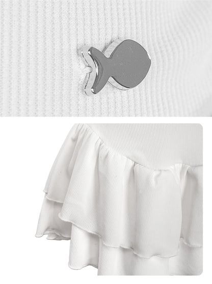 Close-up of a white sweater with a gray fish-shaped button and a white skirt with ruffles.