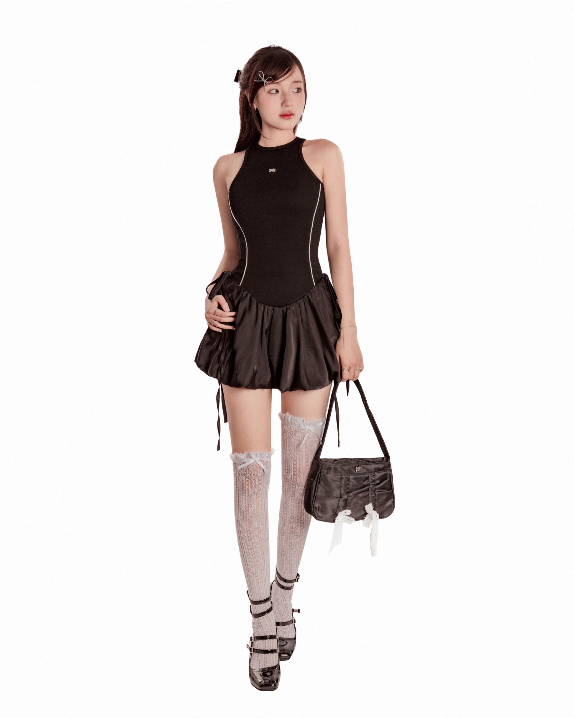 Woman wearing a black dress with a skirt, stockings, and shoes on a white background