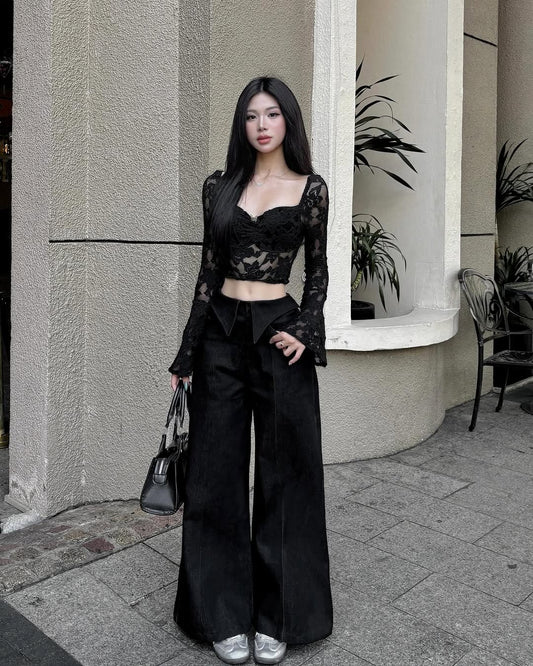 Woman in a black outfit standing outside a building with plants.