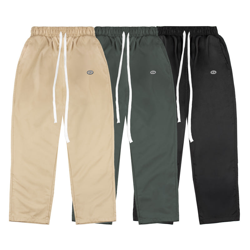 Three pairs of pants in beige, green, and black on a white background