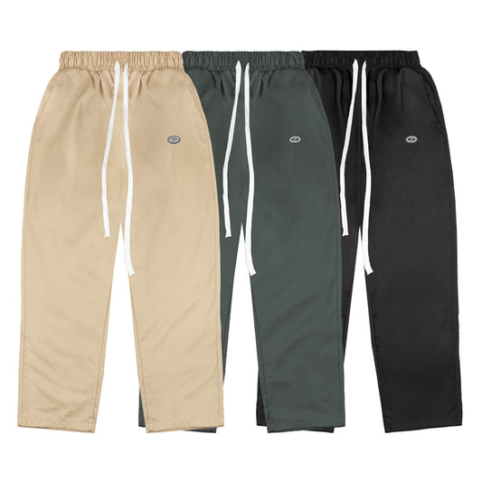 Three pairs of pants in beige, green, and black on a white background