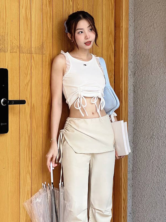 Woman in a white top and beige pants standing in front of a wooden door.