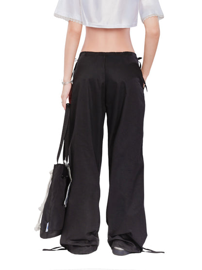 Person wearing black wide-leg pants with a white top on a white background