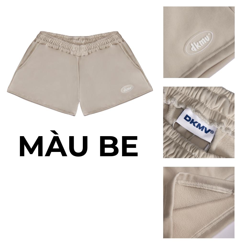 Beige shorts with DKMV branding on a white background