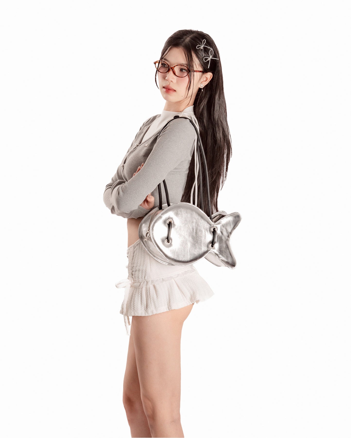 Woman holding a silver fish-shaped bag on a white background
