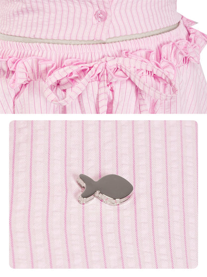 Pink and white striped outfit with ruffled details and a gray fish-shaped object on a matching pink background.