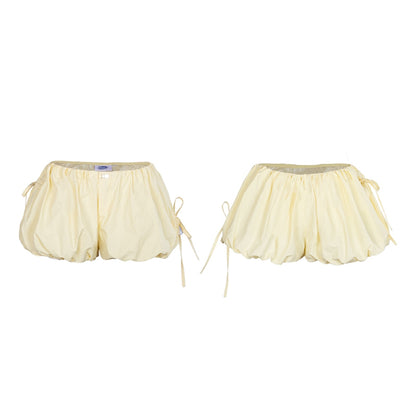 Pair of cream-colored shorts with a sheer overlay on a white background