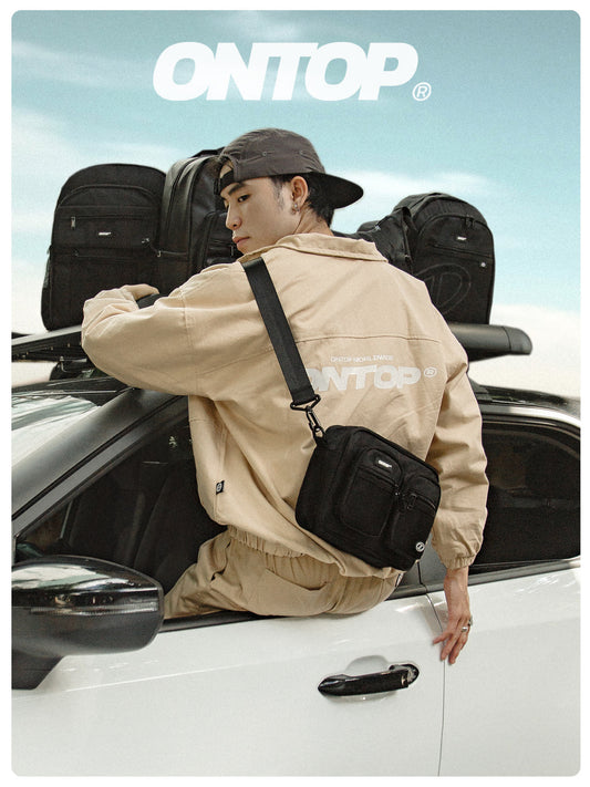 Person with a black bag and 'ONTOP' jacket standing next to a car with 'ONTOP' branding.