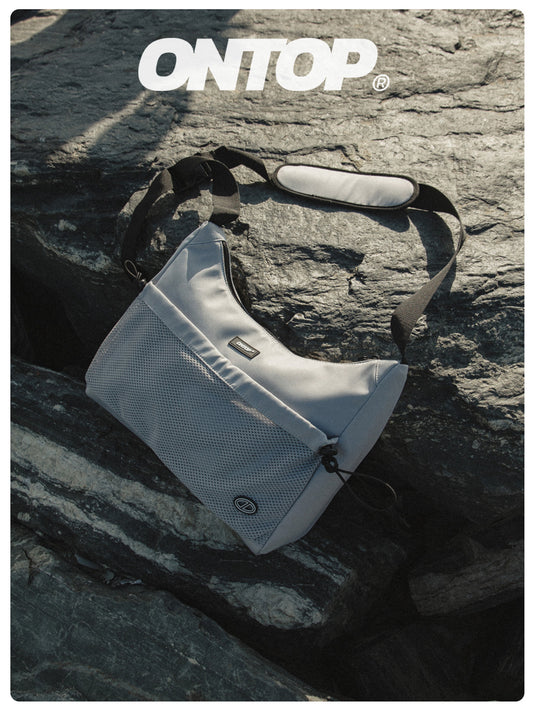 White shoulder bag on a rocky surface with 'ONTOP' branding.