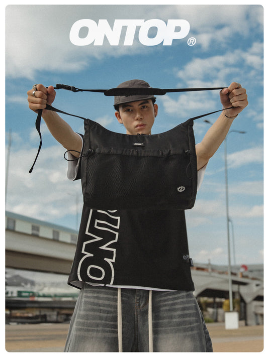 Person holding a black vest with 'ONTOP' branding against a cloudy sky.