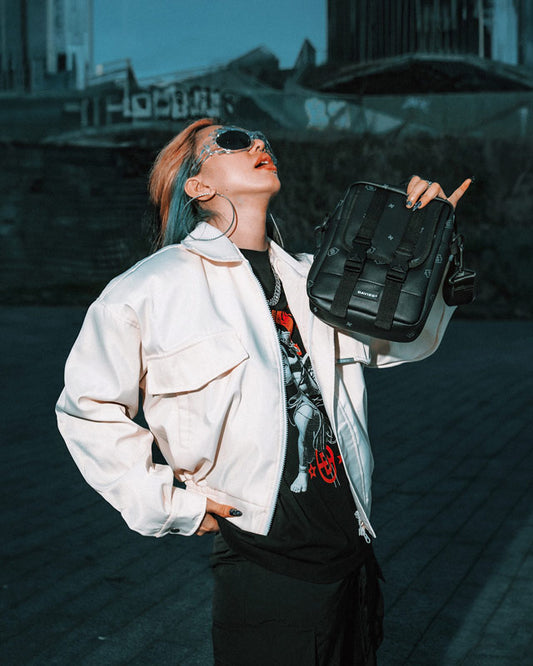 Person with colorful hair holding a black backpack against an urban background
