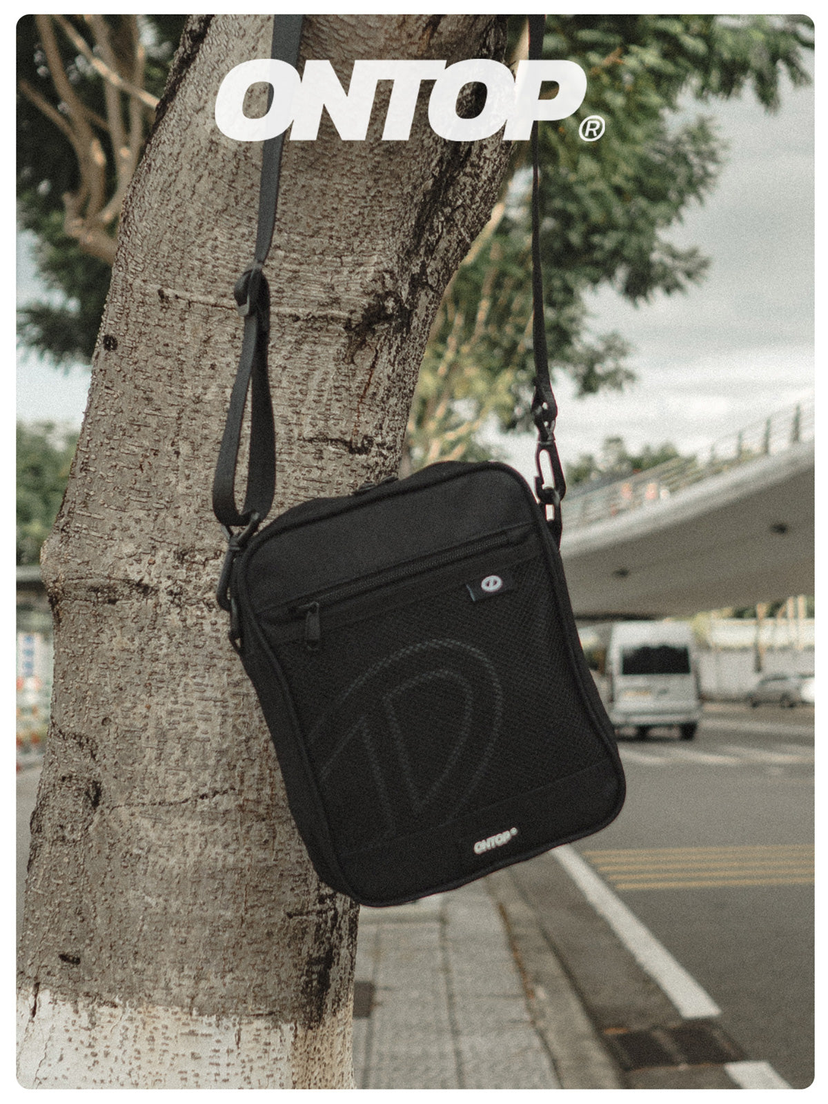 Black shoulder bag hanging on a tree with 'ONTOP' branding.