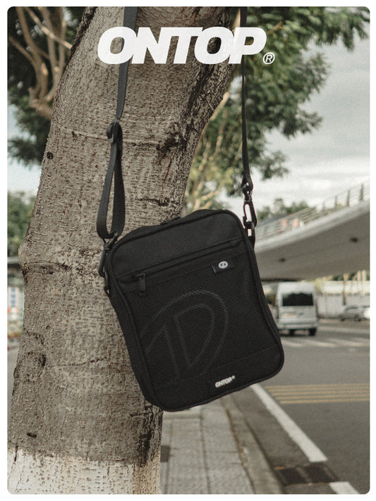 Black shoulder bag hanging on a tree with 'ONTOP' branding.