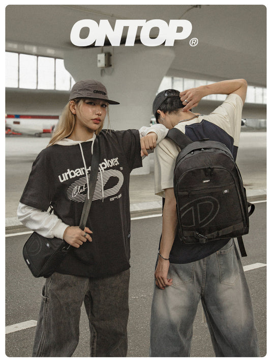 Two people standing together, one holding a backpack with 'ONTOP' branding, in an indoor setting.