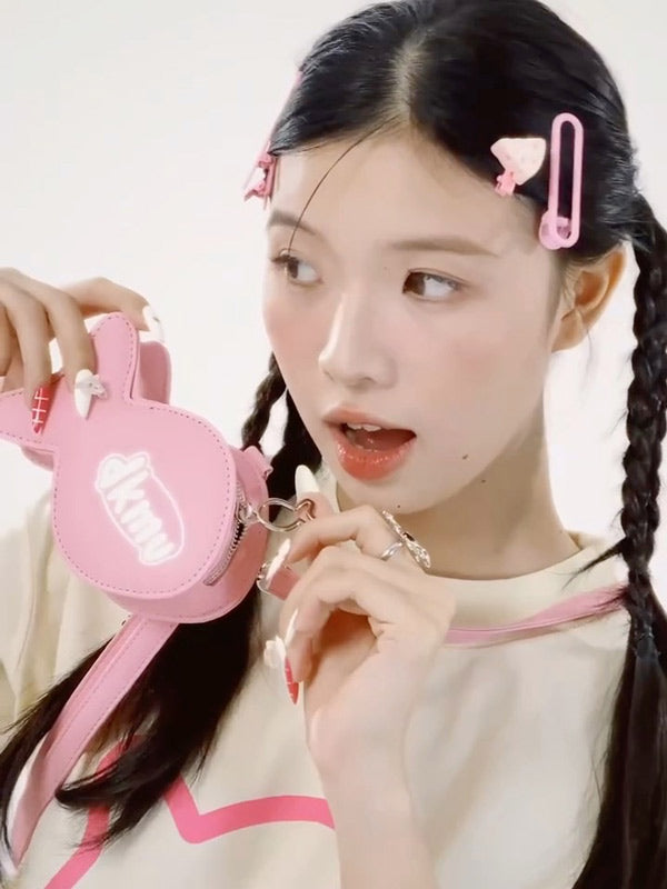 Young girl with braided hair holding a pink bag against a white background