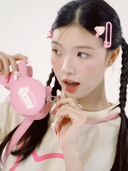 Young girl with braided hair holding a pink bag against a white background