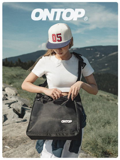 Person holding a black bag with 'ONTOP' branding outdoors