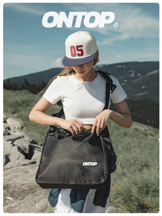 Person holding a black bag with 'ONTOP' branding outdoors