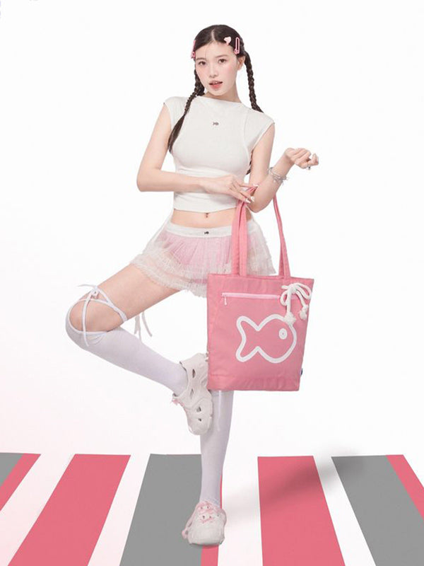 Person holding a pink tote bag with a fish design on a white background