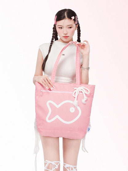 Person holding a pink tote bag with a fish design on a white background