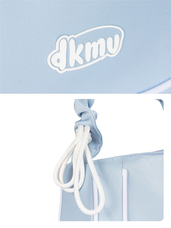 Light blue drawstring bag with white drawstring on a light blue background, featuring the brand 'dkmv'.