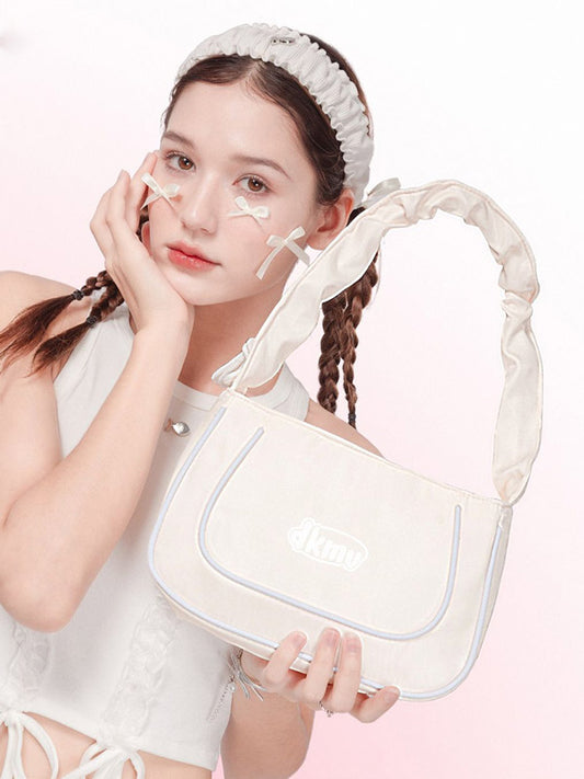 Woman holding a white handbag with a soft pink background