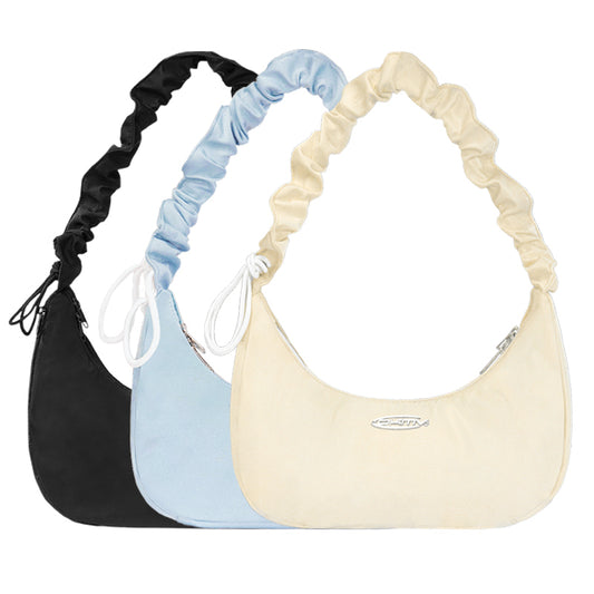 Three handbags in black, blue, and beige with matching scrunchies on a white background